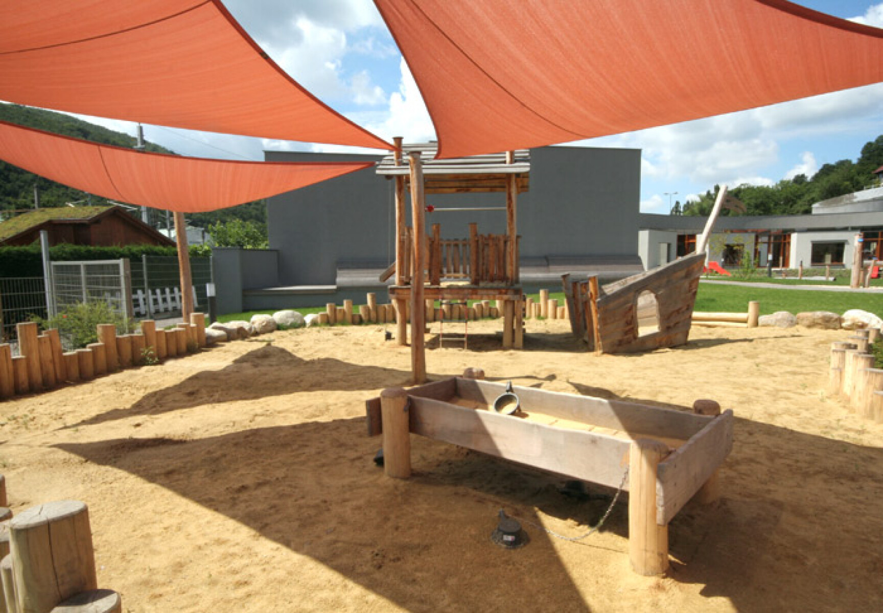 sandspielanlage mit beschattung und einem spielhaus