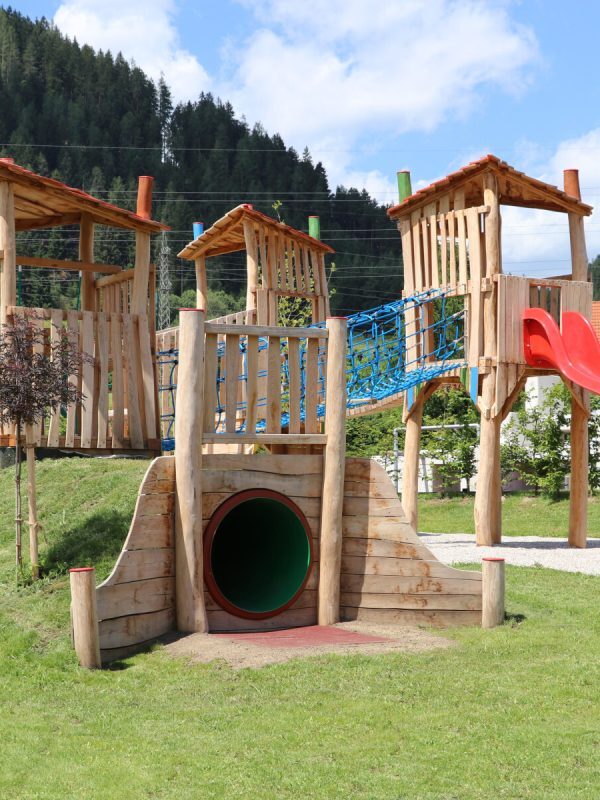Holzspielanlage mit Türmen, Tunnel und roter Rutsche