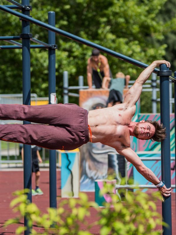 Sportler beim Training an einer Calisthenics-Anlage im Freien